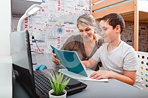 Schoolboy educate online. Mother helps his son with homework