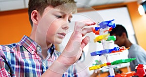 Schoolboy experimenting molecule model in laboratory at school