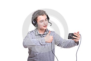 Schoolboy guy with headphones playing on mobile phone. Teenager happy screams . Young man won an online game on a smartphone.
