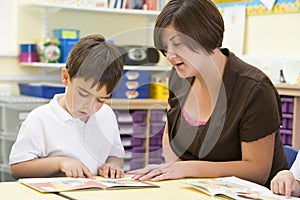 A schoolboy and his teacher reading in class