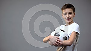 Schoolboy holding football ball and looking to camera, active leisure hobby