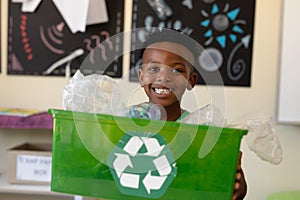 Schoolboy holding a green crate with a white recycling logo on it