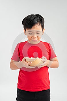 Schoolboy holds a yellow bowl full of candy. Portrait of a child of asian appearance and delicious food