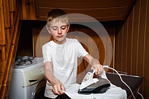 Schoolboy irons his clothes electric iron. Child does homework