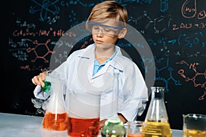 Schoolboy in laboratory wear lab coat learning science of chemistry. Erudition.