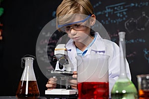 Schoolboy in laboratory wear lab coat learning science of chemistry. Erudition.