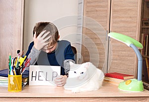 Schoolboy with learning difficulties doing home assignment. Sad photo