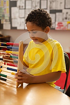 Schoolboy learning mathematics with abacus in a classroom