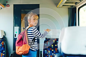 Schoolboy leaving wagon. Cute preteen boy getting off train. Little passenger standing inside train