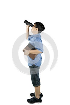 Schoolboy looking at something with a binocular