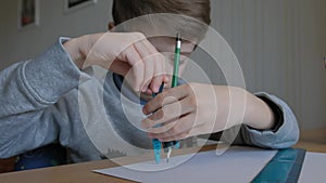 Schoolboy make homework and using drawing compass and ruler to draw a car