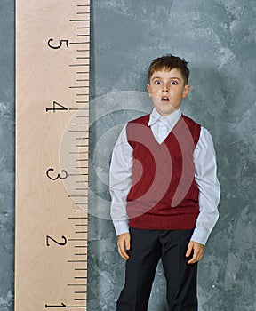 Schoolboy next to the measuring ruler