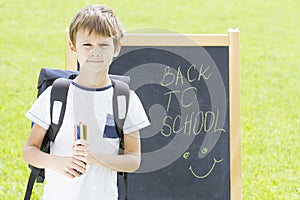 Schoolboy with pens and backpack against the blackboard. Education, Back to school concept