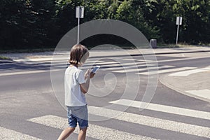 Schoolboy with phone on pedestrian crossing going home