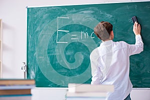 Schoolboy physicist in front of green board