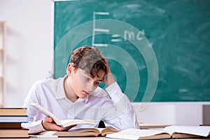 Schoolboy physicist in front of green board