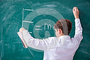 Schoolboy physicist in front of green board