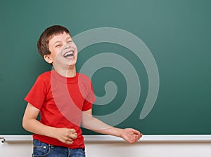 Schoolboy play and laugh near a blackboard, empty space, education concept