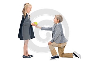 Schoolboy presenting apple to girl