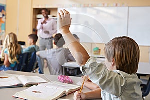 Schoolboy raising hand to answer question in a school class