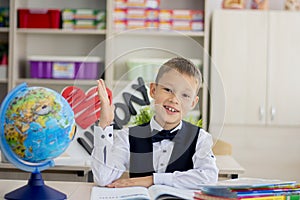 A schoolboy at school sits in class and stretches his hand