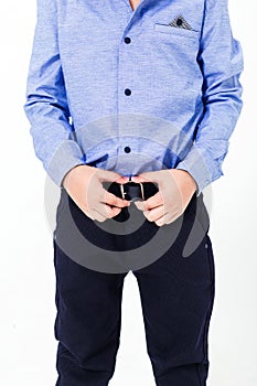 Schoolboy in a school uniform on a white background. The boy demonstrates the belt in black trousers.