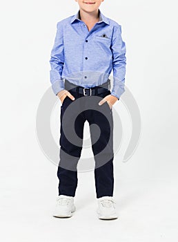 Schoolboy in a school uniform on a white background. The boy demonstrates a shirt, trousers, a belt and sneakers.