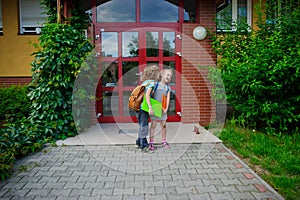 Schoolboy with schoolgirl stand at doors of school and about something mutter.