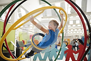 Schoolboy in science centre using human gyroscope, side view