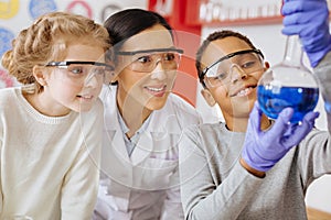 Schoolboy showing flask with substance proudly to teacher and classmate