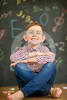 Schoolboy sits on the background of a painted school board