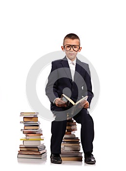 Schoolboy sitting on the huge stack of books