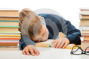 schoolboy is sleeping at a table between piles of books on a white background