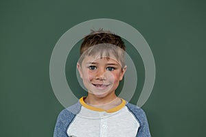 Schoolboy standing against greenboard in a classroom