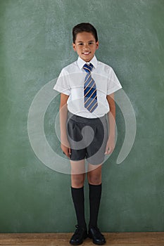 Schoolboy standing in front of chalkboard in classroom