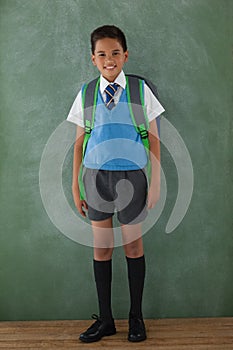 Schoolboy standing in front of chalkboard in classroom