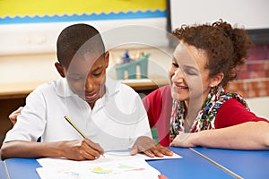 Schoolboy Studying In Classroom With Teacher photo