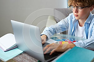 Schoolboy studying at home looking at tutor at laptop screen during quarantine isolation period