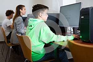 Schoolboy using computer at lesson, teacher teaching pupils in class room