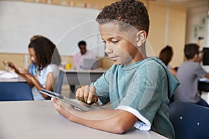 Schoolboy using tablet in elementary school class, close up