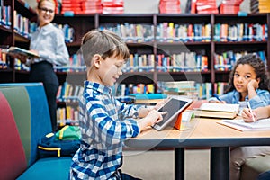 schoolboy using tablet at library