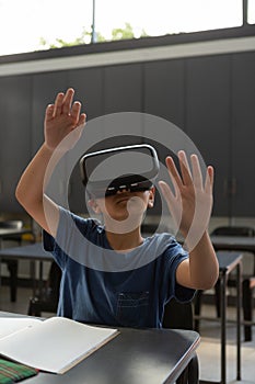 Schoolboy using virtual reality headset at desk in a classroom