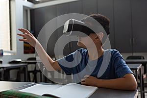 Schoolboy using virtual reality headset at desk in a classroom