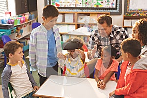 Schoolboy using virtual reality headset with his classmate and teacher