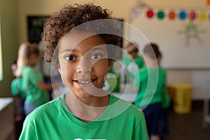 Schoolboy wearing a green t shirt with a white recycling logo on it