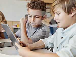 Schoolboys working together with tablet computer, close up