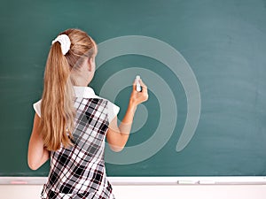 Schoolchild writing on blackboard. photo