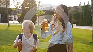 Schoolchildren a boy and a girl in the school yard drink juice during a break between lessons.