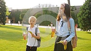 Schoolchildren a boy and a girl in the school yard drink juice during a break between lessons.
