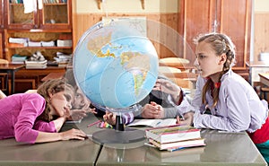 Schoolchildren exploring globe in classroom